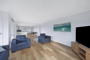 沃纳姆堡Logans Beach Apartments - Greenviews的客厅配有2把蓝色椅子和平面电视