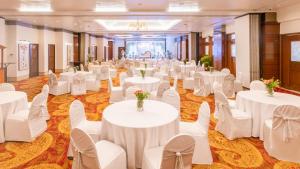 孟买Hotel Kohinoor Continental,Airport的宴会厅配有白色的桌子和白色的椅子