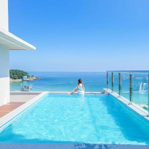 釜山Paul Mare Pool Villa的坐在游泳池俯瞰大海的女人