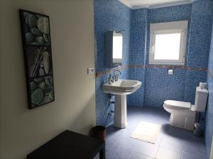 NavecesLa Cariñosa的蓝色瓷砖浴室设有水槽和卫生间