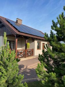 卡尔维亚ZIELONE MIEJSCE - klimatyczny domek nad morzem的一座拥有太阳能屋顶和一些树木的房子