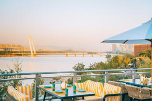 西安西安浐灞艾美酒店的阳台配有桌椅,享有河景