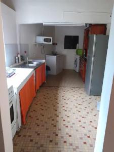 旧阿比唐Maison La voûte plage à 50m et rivière à proximité的厨房配有橙色橱柜和瓷砖地板。