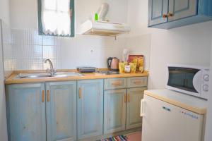 凯瑟拉Koralia Apartments的厨房配有蓝色橱柜、水槽和微波炉