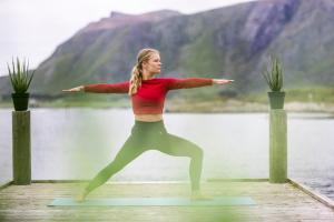 FarstadHustadvika Havhotell - by Classic Norway Hotels的一名在水体附近的码头上做瑜伽的女人