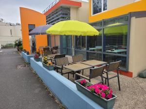 达迪利Premiere Classe Lyon Nord Dardilly的庭院配有桌椅和黄色雨伞。