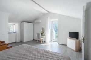 索伦托Casale del Nonno的一间白色卧室,配有床和电视