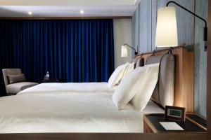 那霸嘉新酒店的卧室配有一张带蓝色窗帘的大型白色床