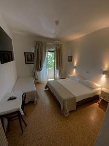 马里纳-迪-皮特拉桑塔Hotel Naviglio的一间卧室设有两张床、一张桌子和一个窗口