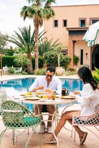马拉喀什La Villa Des Golfs & PinkCactus的坐在桌旁的男女