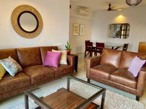 孟买Kanakia Paris D wing at BKC, Near Asian Heart Hospital, A Luxury Stay by Connekt Homes的客厅配有2张棕色沙发和镜子