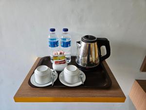 AmbaritaThyesza Hotel的一个带咖啡壶、杯子和水瓶的托盘