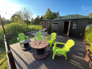 叶卡布皮尔斯Wake nams ar pirtiņu的一个带绿色椅子和桌椅的甲板