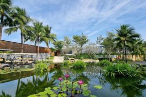 富国Moon Villa Phu Quoc - 3 Bedroom - Private pool的种有棕榈树的花园和一个种有鲜花的池塘