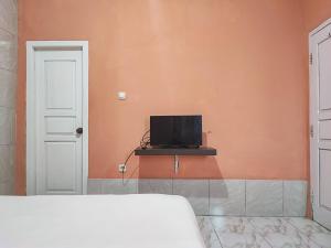 占碑市Reddoorz Syariah Near Kantor Gubernur Jambi的一间卧室配有一张床,墙上配有电视