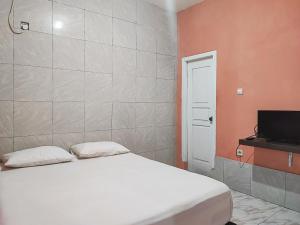 占碑市Reddoorz Syariah Near Kantor Gubernur Jambi的卧室配有白色的床和电视。