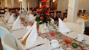 乌洛夫斯特伦Hotel Fritza - tidigare "Hotel Fritzatorpet"的一张长桌,上面有白色的桌子和红色的花