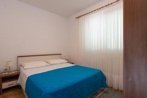 维尼斯切Apartments Mirko的白色卧室设有蓝色的床和窗户