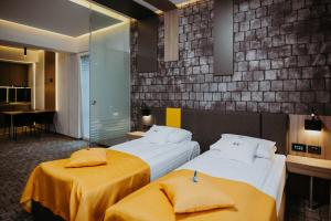 CisnădieHotel Epic Centrum的酒店客房带两张带黄床单的床