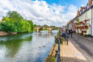 布由德利Bewdley River Cottage - Free private gated parking for 2 cars - River front location的城市里一条河,有一座桥在后面