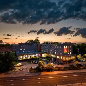 奥尔什丁Best Western Plus Hotel Olsztyn Old Town的一座晚上有停车位的建筑