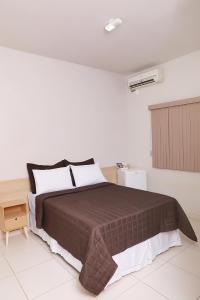 QuirinópolisHotel Borges的一间白色客房内配有一张大床的卧室
