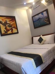 沙塘潭Khách Sạn Blue Sky的墙上挂有绘画的客房内的两张床