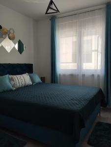 斯雷姆斯卡米特罗维察Apartman Green!!的一间卧室配有一张带蓝色窗帘的床和一扇窗户