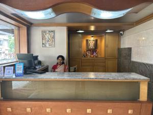 浦那Hotel Ashirwad的坐在办公室柜台的女人