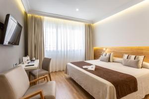 塞维利亚蒙泰卡尔梅洛酒店的酒店客房配有一张床、一张书桌和一台电视。