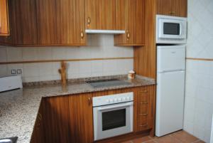 里奥帕尔艾尔米拉多德瑞奥帕威乔旅馆的厨房配有木制橱柜和白色炉灶烤箱。