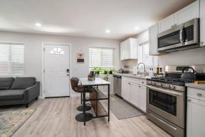 圣地亚哥Urban Oasis: San Diego Bungalow Escape的厨房配有白色橱柜、桌子和沙发