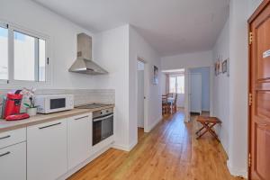 大加那利岛拉斯帕尔马斯Apartments Vegueta Suite的厨房铺有木地板,配有白色橱柜。