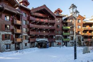 阿克1950Arcs 1950 Appartement Luxe type chalet 5 à 7 personnes Vue imprenable sur le Montblanc skis aux pieds的雪中大建筑,有街灯