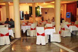 米蒂利尼拉西亚酒店的用餐室配有白色的桌子和白色的椅子