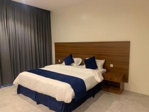 Al Namasاجنحة ريام的一间卧室配有一张大床和木制床头板