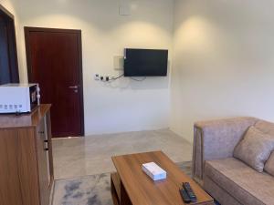 Al Namasاجنحة ريام的带沙发和电视的客厅