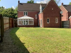 翰索Large Executive 4-Bed Detached House in Miskin, Cardiff-sleeps up to 10的一座带栅栏和草地庭院的房子