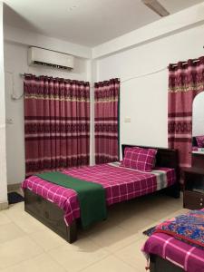 达卡Mohammadia Restaurant & Guest House Near United Hospital的一间卧室设有两张床和红色窗帘