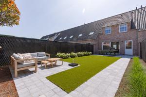 米德尔克尔克Modern house JULIE with spacious garden and garage的一个带沙发和桌子的花园以及草地