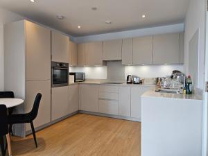 克罗伊登Santina Apartments的厨房配有白色橱柜和桌子