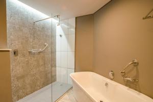 德班德班乌兰加万豪Protea酒店的带浴缸和玻璃淋浴间的浴室。