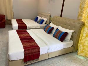 Ban Phayomบุญจินดา รีสอร์ท的配有2张床铺的酒店客房,提供白色床单和色彩缤纷的枕头