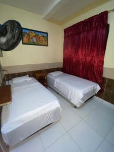 莱蒂西亚Hostal Yahuarcaca的客房设有两张床和墙上的风扇。