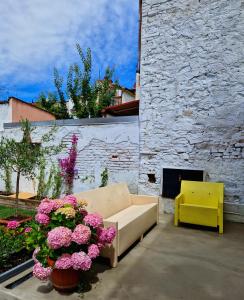 维亚雷焦Mi Garba B&B的一张沙发,坐在开满粉红色花卉的庭院里