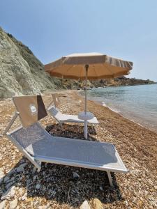帕尔马迪蒙泰基亚罗Tendu' Punta Bianca Glamping Camp的海滩上的2把躺椅和1把遮阳伞