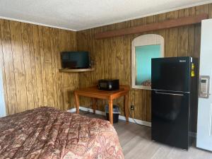 BaxleyPinelodge Motel的一间卧室配有冰箱、桌子和电视