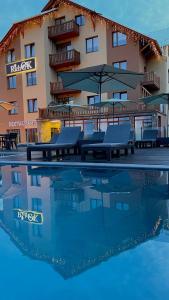 亚布卢尼齐亚Rich OAK - Багатий Дуб的游泳池旁的酒店设有桌子和遮阳伞