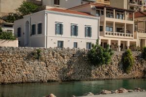 锡蒂亚Palazzo di Sitia Luxury Suites的一条河旁石墙上的白色建筑