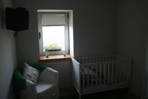梅桑弗里乌Casa da Oliveira的一张带窗户和椅子的房间里婴儿床